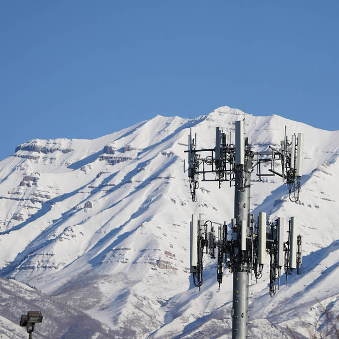 A 5G cell tower in front of snow covered mountains against a blue sky. Photographer: George Frey/Bloomberg