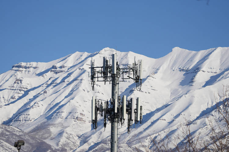 A 5G cell tower in front of snow covered mountains against a blue sky. Photographer: George Frey/Bloomberg