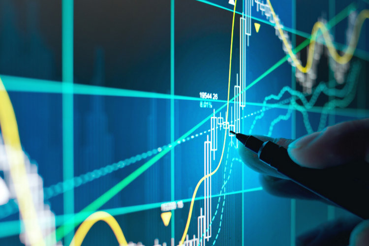 A business person tracking the technical movement of a stock chart on a computer screen.; Shutterstock ID 1050436808