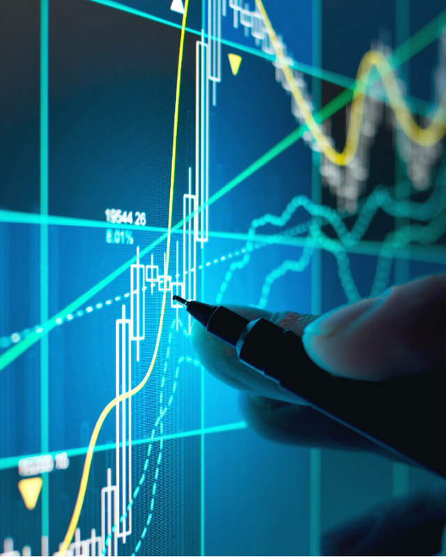 A business person tracking the technical movement of a stock chart on a computer screen.; Shutterstock ID 1050436808