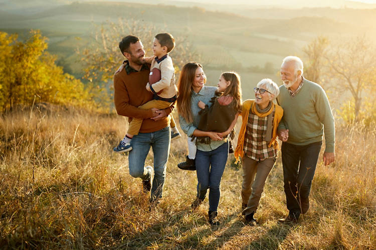 Happy extended family communicating while walking in autumn day on a hill.