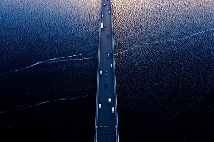 Aerial of Tasman bridge over wide flowing Derwent river in Tasmania Australia, with traffic, cars and trucks, crossing at sunset.