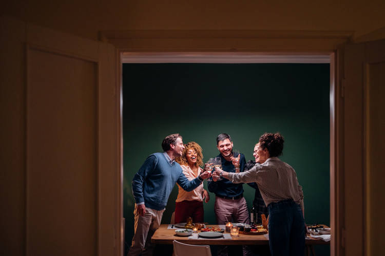 Cheerful group of multi-ethnic people having fun at dinner party and toasting with alcohol.