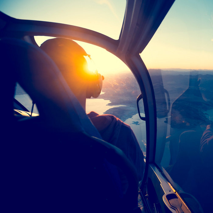 Flying in a helicopter over lake mead in Arizona. View is from behind with a view of  lake mead near the grand canyon. Time of ay is sunset or sunrise with a beautiful view and blue sky. Copy space on right. Can be flipped.