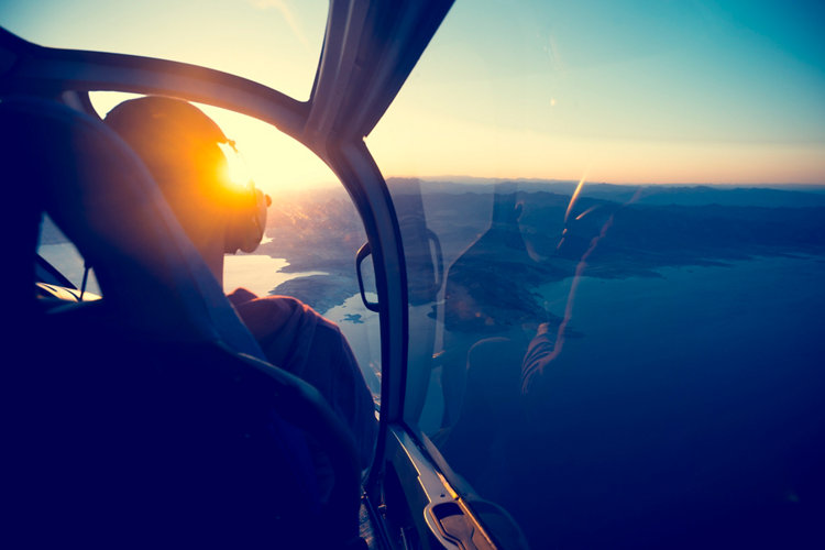 Flying in a helicopter over lake mead in Arizona. View is from behind with a view of  lake mead near the grand canyon. Time of ay is sunset or sunrise with a beautiful view and blue sky. Copy space on right. Can be flipped.