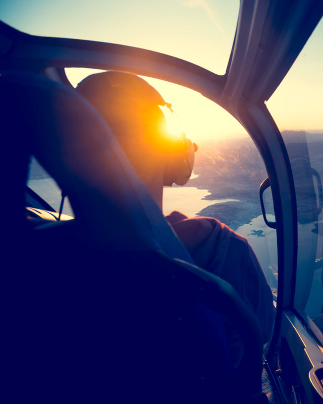 Flying in a helicopter over lake mead in Arizona. View is from behind with a view of  lake mead near the grand canyon. Time of ay is sunset or sunrise with a beautiful view and blue sky. Copy space on right. Can be flipped.