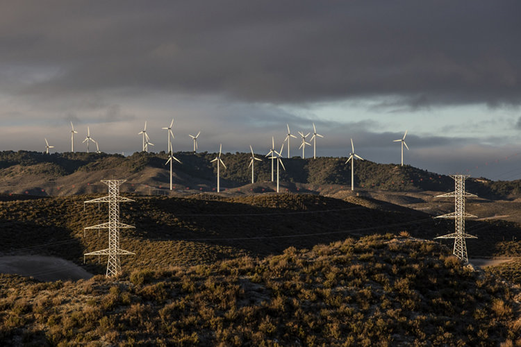 Wind turbines and electricity transmission towers on a hillside. Photographer: Angel Garcia/Bloomberg